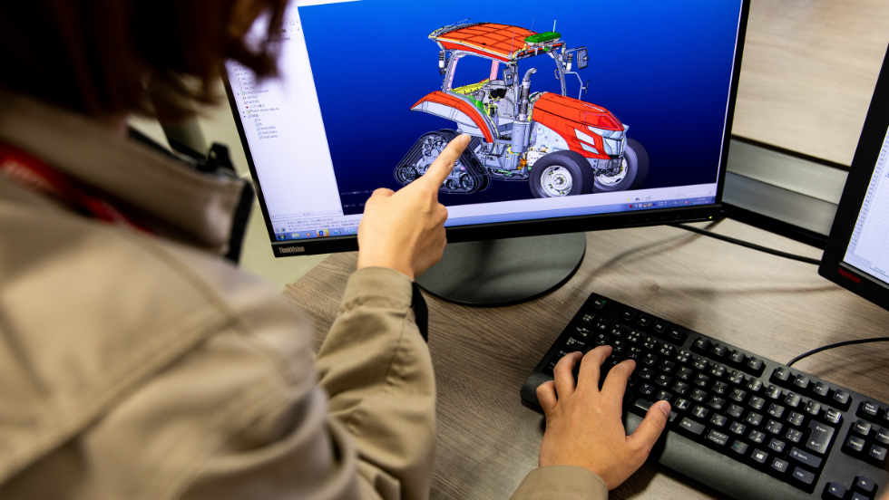 Un employé de Yanmar examine un concept de design de tracteur pensé pour l’agriculture intelligente sur l’écran d’un ordinateur Lenovo
