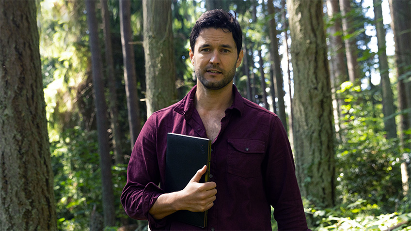 In forest holding laptop in one hand