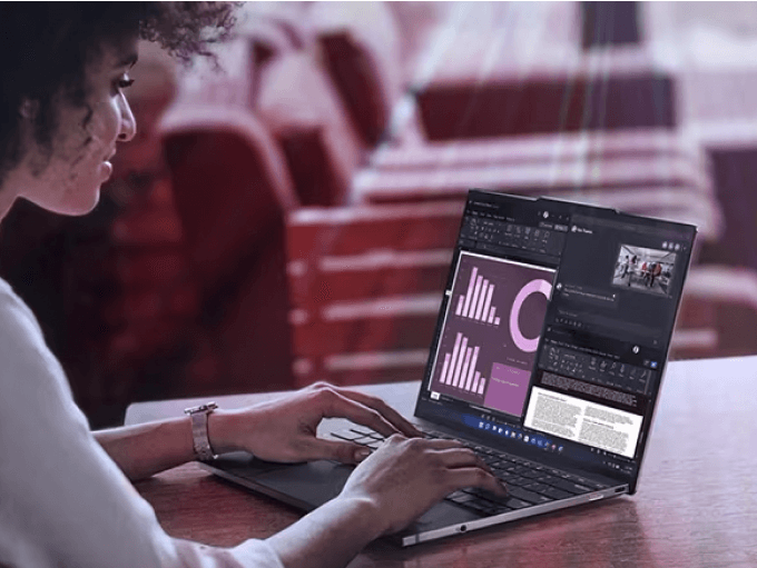 A woman types on a laptop in a sunny room.