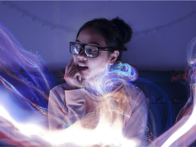 A woman looks thoughtfully aside as streaming lights surround her. 