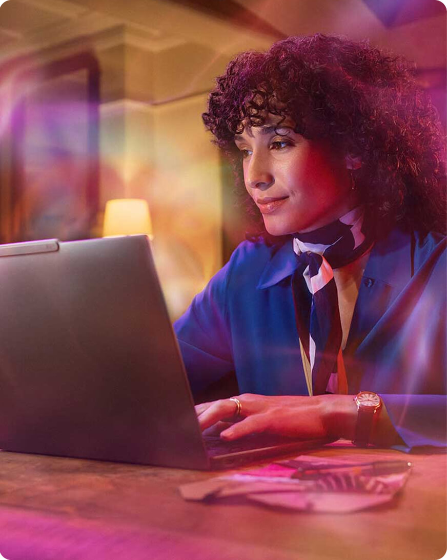 A woman using a laptop with colorful overlays around her. 