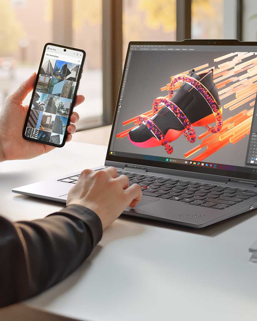 A person holding their phone and comparing the pictures to the content they’re creating on their laptop. 