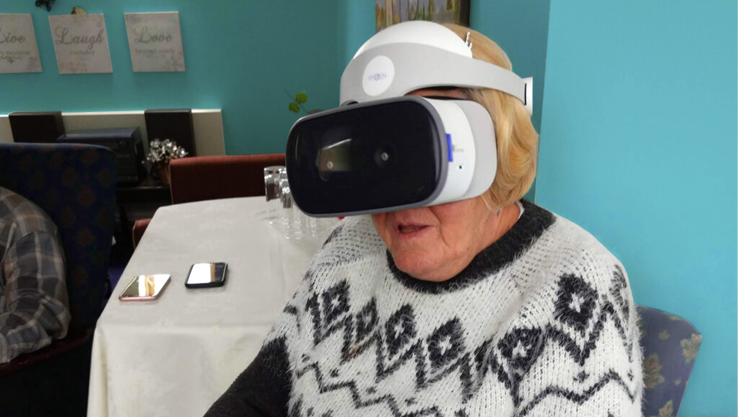 A senior woman sits while using a Lenovo Mirage VR headset