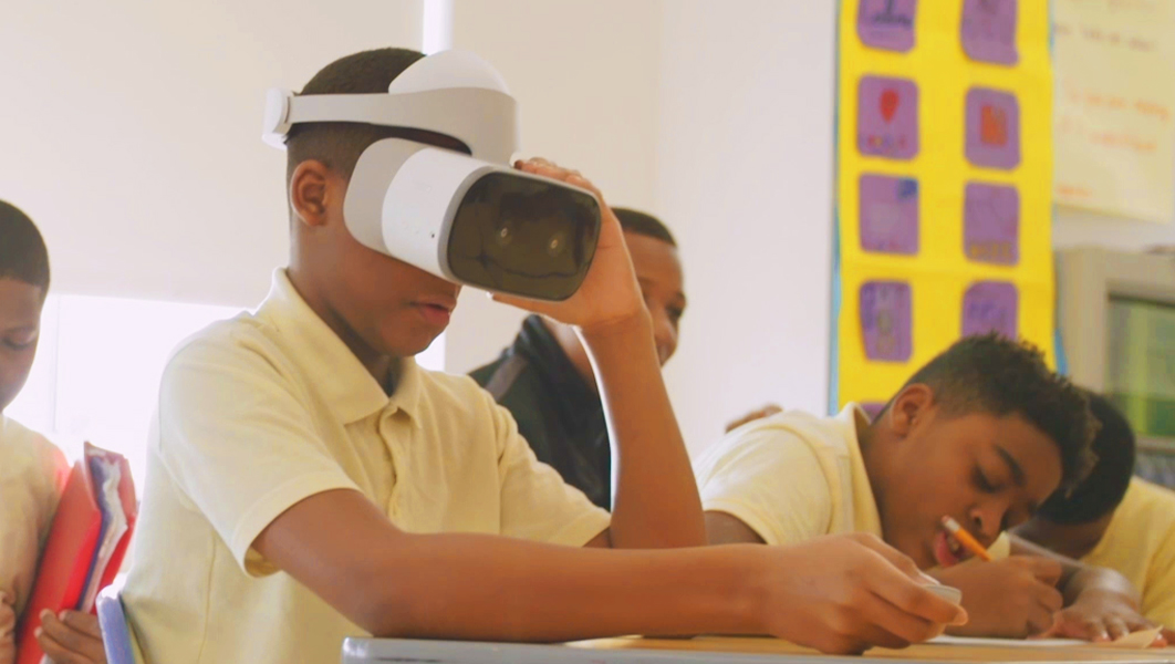 A student uses a Lenovo Mirage™ Solo VR headset while sitting at a desk in a classroom