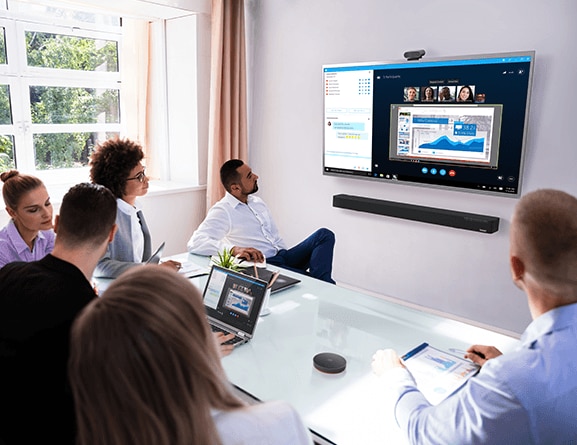 Six people in a conference room with Lenovo ThinkSmart Bar audio bar mounted on wall, underneath a display