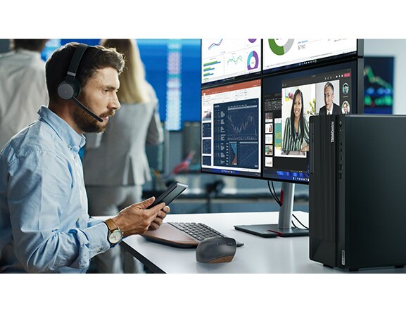Office worker with smartphone (sold separately), looking at four monitors (all sold separately) connected to ThinkCentre M90t Gen 3 Tower, with wireless keyboard and mouse (also sold separately)