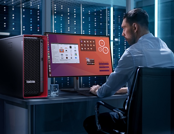 Data scientist looking at multiple apps on a large monitor, typing on a keyboard, with Lenovo ThinkStation P7 workstation to the left