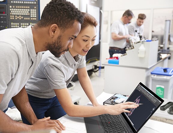 Lenovo ThinkPad P14s Gen 3 Notebook auf einem Schreibtisch mit zwei Personen, die sich vorbeugen und auf das Display zeigen.