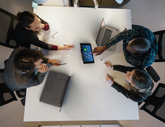 Vue de dessus de 4 personnes autour d'une table utilisant l’écran Lenovo ThinkSmart Controller pour Zoom Rooms.