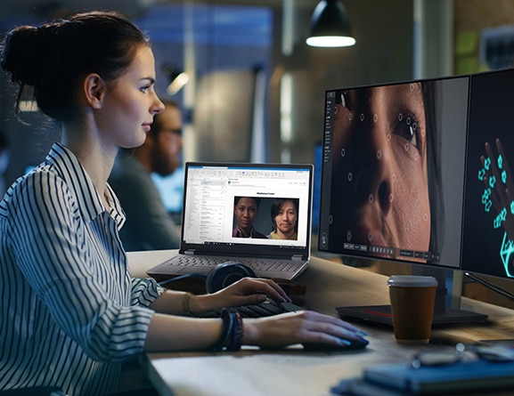 Graphic designer looking at close-up of image on large monitor, next to an opened Lenovo ThinkPad P16 Gen 2 (16″ Intel) laptop