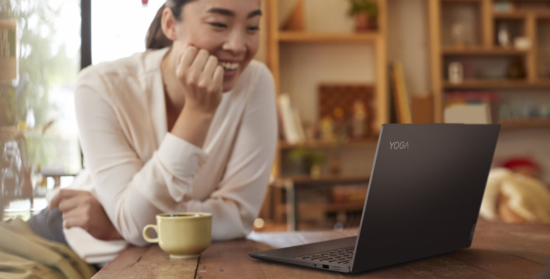 Mujer tomando un café con la laptop Yoga Slim 7 Pro 14” AMD gris pizarra
