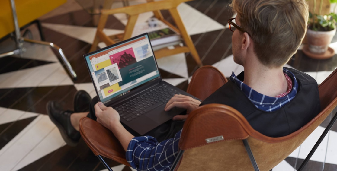 Hombre trabajando con la laptop Yoga Slim 7 Pro 14” AMD gris pizarra en la falda
