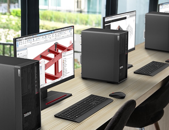 A row of Lenovo ThinkStation P348 Tower workstations with monitors and wireless keyboards and mice lined up along a window table.