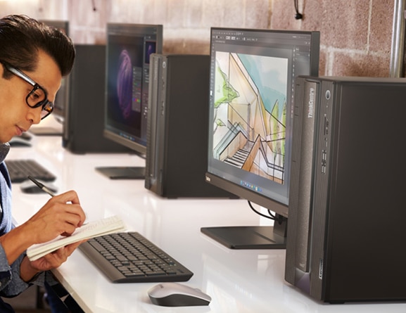 Person taking notes in front of a right side angled Lenovo ThinkCentre Neo 70t tower, monitor, keyboard and mouse. 