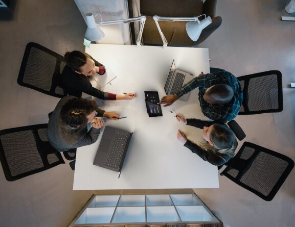 Overhead shot of 4 people at a table using the Lenovo ThinkSmart Controller display for Microsoft Teams.