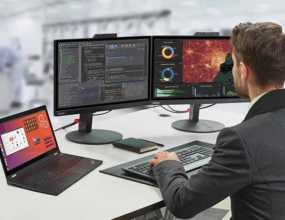 En mann som sitter ved et skrivebord med den mobile workstationen for Lenovo ThinkPad P15 Gen 2 sammen med to store skjermer som viser medie- og underholdningsbransje.