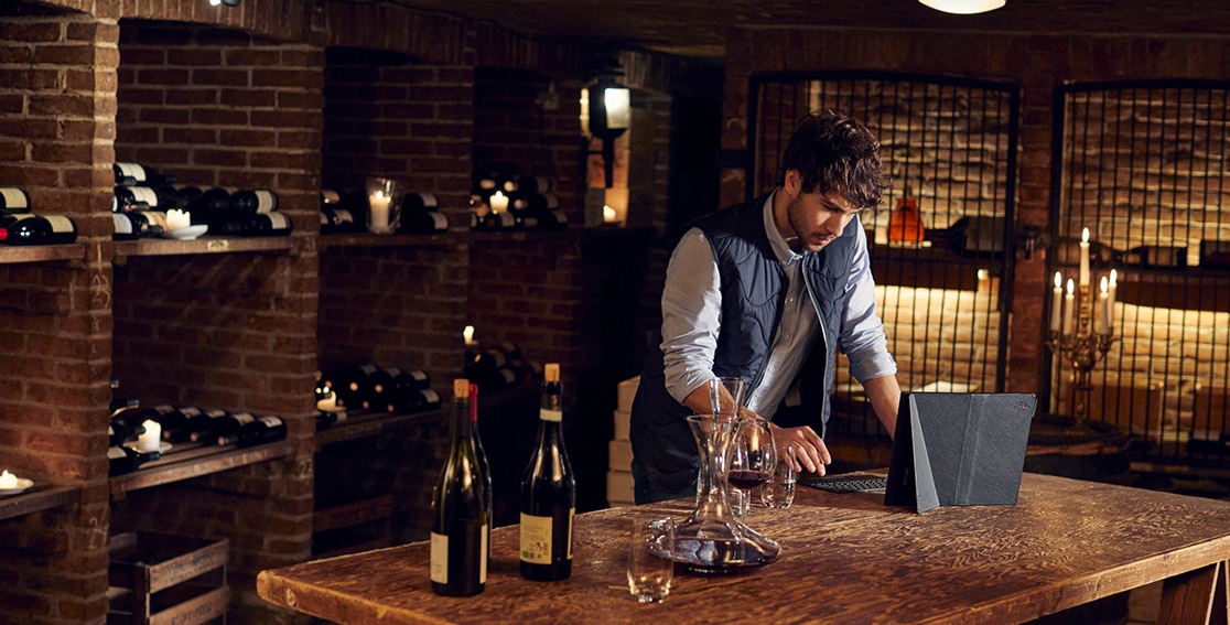 barman con laptop plegable y botellas de vino