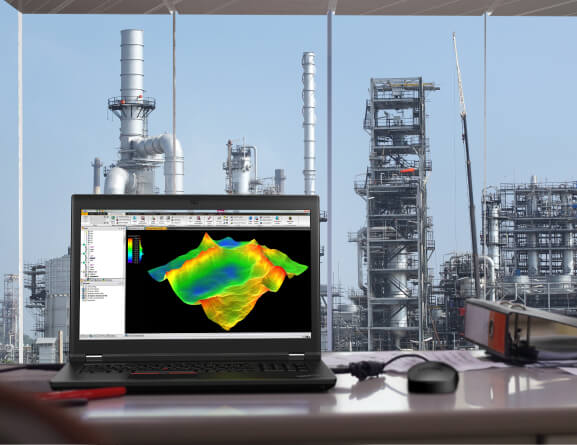 Frontaufnahme der mobilen Workstation Lenovo ThinkPad P17 auf einem Schreibtisch mit Blick auf eine Erdöl- und Erdgasgewinnungsanlage.