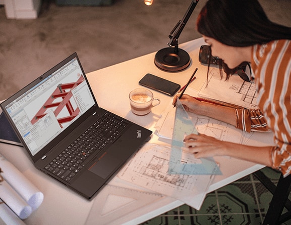Lenovo ThinkPad P15v mobile workstation—pictured on a drafting table in front of a person drawing plans with a triangle