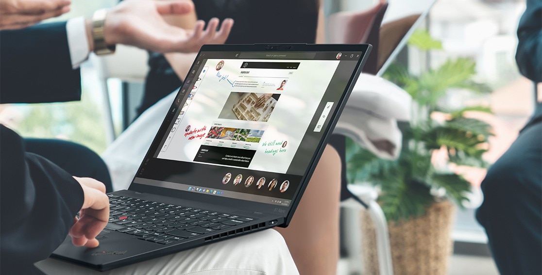 Une personne tape sur le clavier du Lenovo ThinkPad X1 Nano posé sur ses genoux, présentant des images et des notes à l’écran.