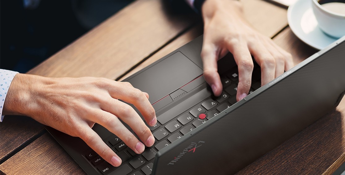Noen som skriver på en Lenovo ThinkPad X1 Nano, tastaturet og det valgfrie vevde toppdekselet vises.