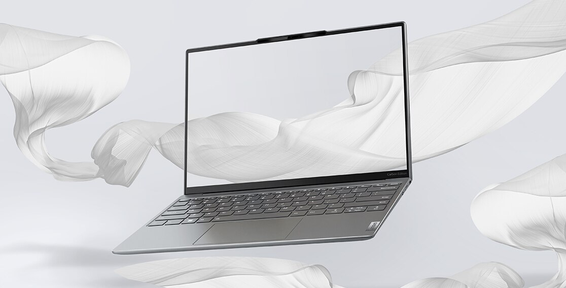 Forward-facing Yoga Slim 7i Carbon laptop, at an angle, seemingly floating  against a backdrop of billowing white sheets, showing display & keyboard