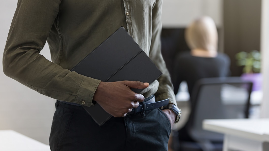 Lenovo Miix 630 - Shot of someone carrying the 2-in-1 laptop with its protective cover closed