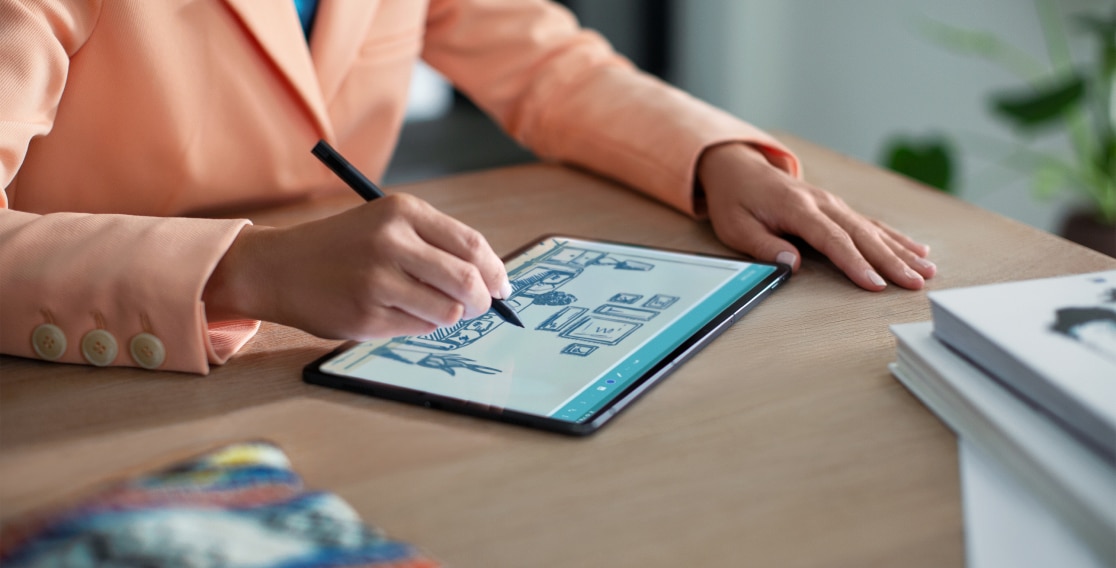 Lenovo Tab P11 Pro lying flat on a table with man using optional Lenovo Precision Pen to draw on tablet