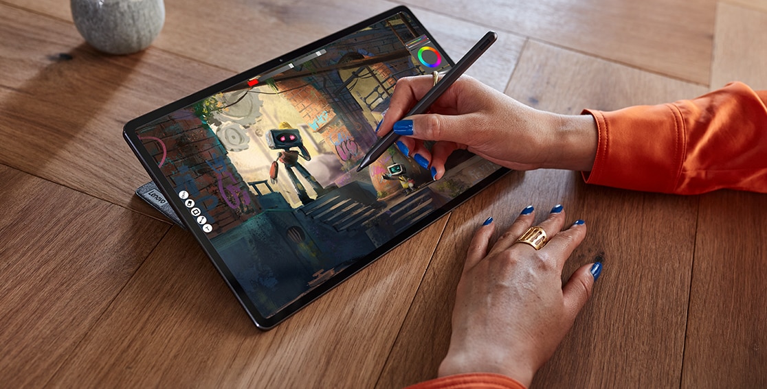 A person uses the Lenovo Precision Pen 3 to interact with the screen of the Lenovo Tab P12 Pro propped before them on a desk, open at a 30-degree angle.