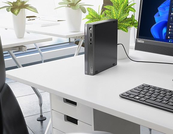Close up of Lenovo ThinkCentre Neo 50q Gen 4 Tiny (Intel), stood vertically on an office desk, next to monitor & keyboard (sold separately)