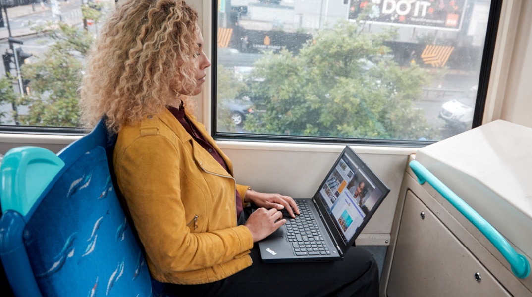 Person sat on a train, with an opened Lenovo ThinkPad P Series mobile workstation on lap, typing on keyboard.