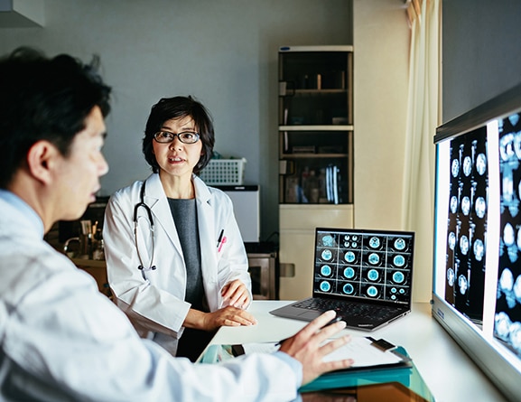Two medical professionals looking at Lenovo P14s Gen 4 (14” AMD) mobile workstation, showing a series of scans and charts on screen