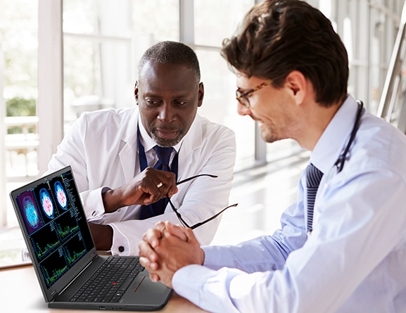 Two medical professionals looking at Lenovo ThinkPad P16v (16” Intel) mobile workstation, showing a series of scans and charts on screen