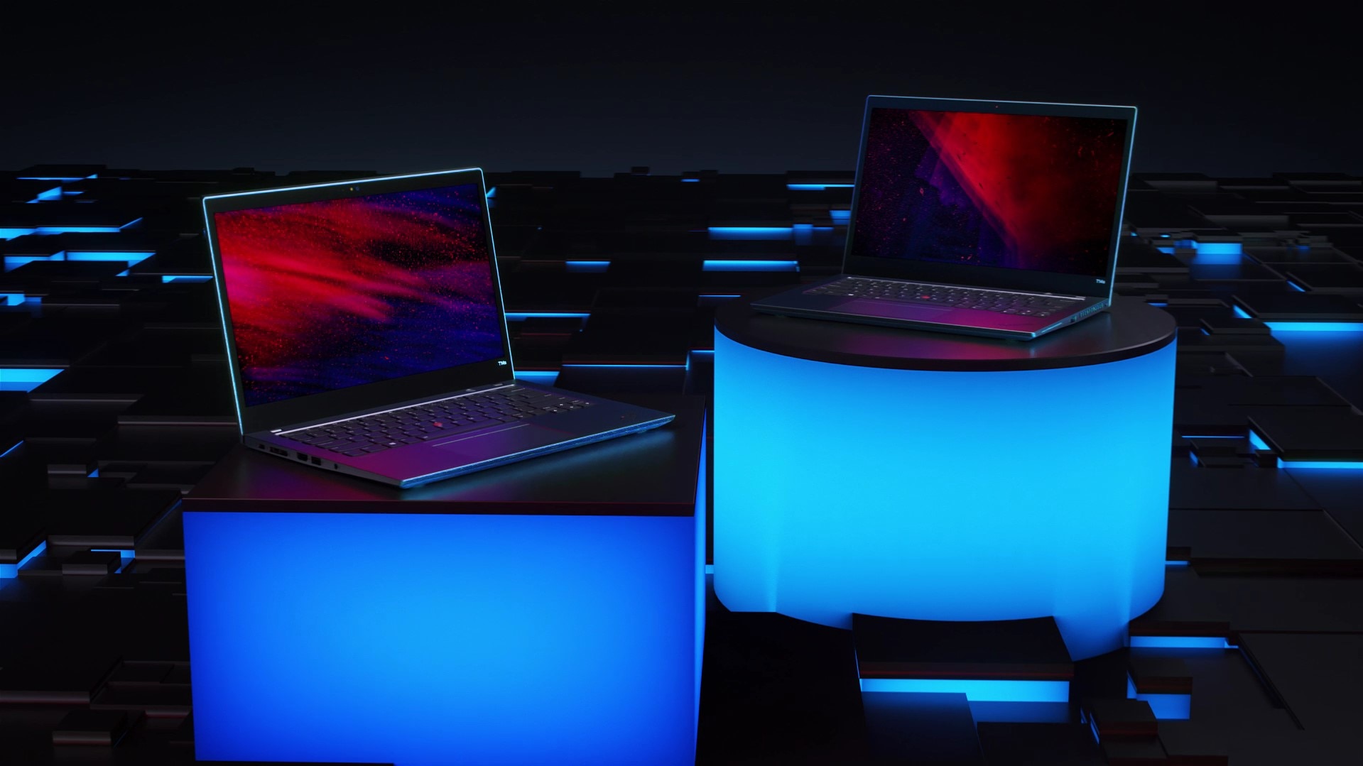 Two Lenovo ThinkPad L Series laptops, opened in laptop mode at a slight angle, each on a display stand with blue neon lighting.