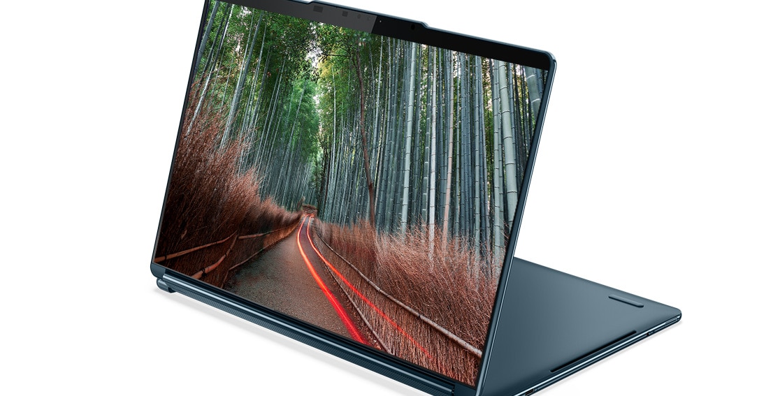 Angle view of the Lenovo Yoga Book 9i Gen 8 (13” Intel) 2-in-1 laptop in stand mode, with an image of a forest road on the display
